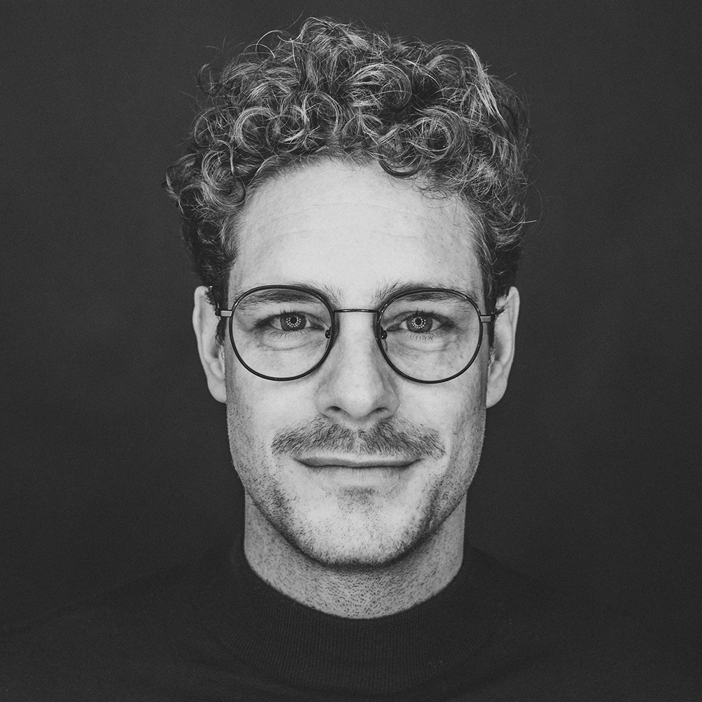 Schwarzweiß Bild Mann mit lockigen Haaren und Brille