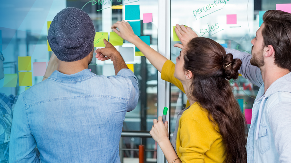 People standing in front of a glass wall with Post-Its