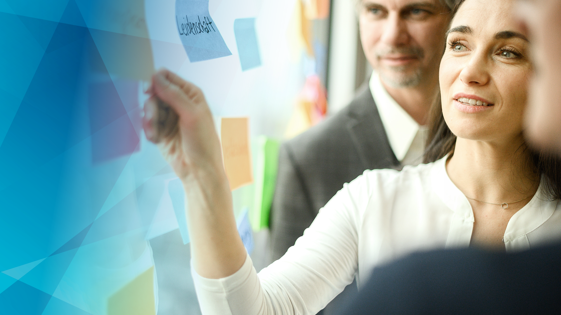 woman with a post it in front of a window; man in the background