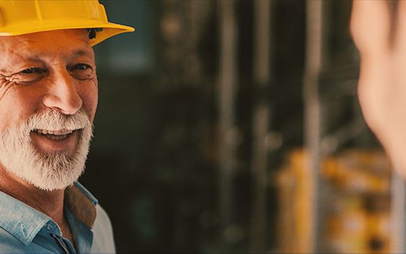 Man with yellow helmet speaks to another man