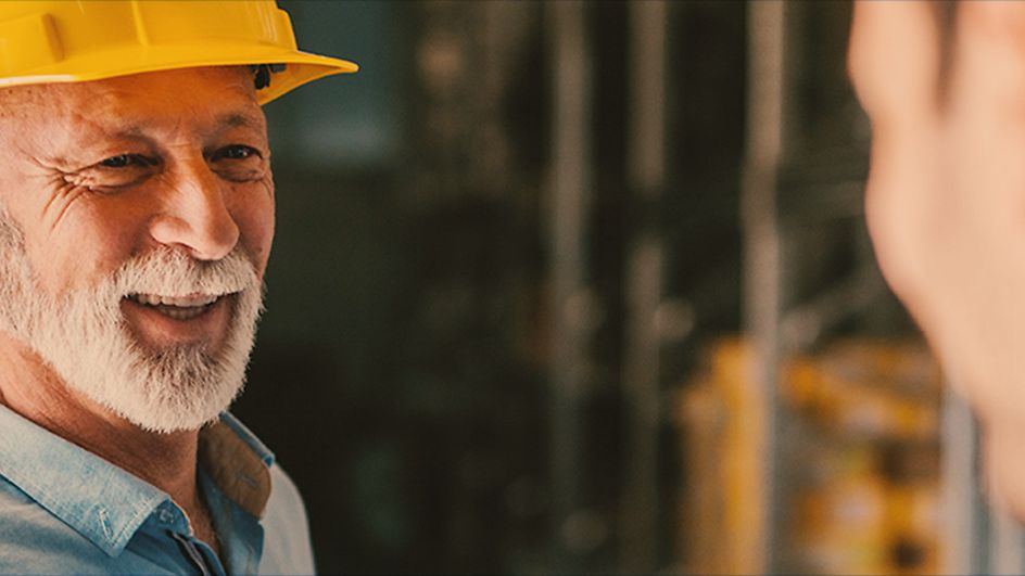 Man with yellow helmet speaks to another man