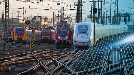 Verschiedene Züge nebeneinander bei der Einfahrt in einen Bahnhof