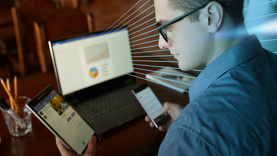 Mann mit Brille vor Laptop, Handy und Tablet