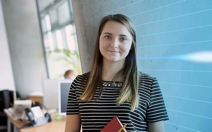 Schülerin im Büro stehend mit Buch in der Hand