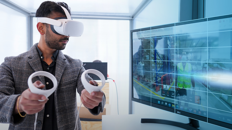 A man with VR glasses standing in front of a screen