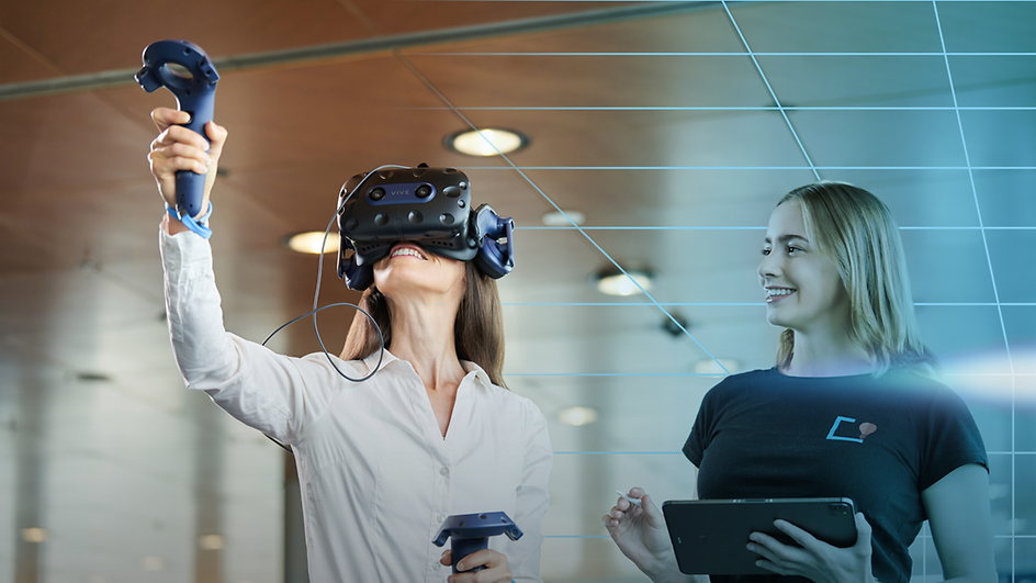Woman with VR glasses on, next to her a second woman with tablet in hand