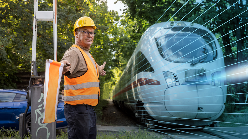 Man in high-visibility waistcoat shows passing train the way with flag