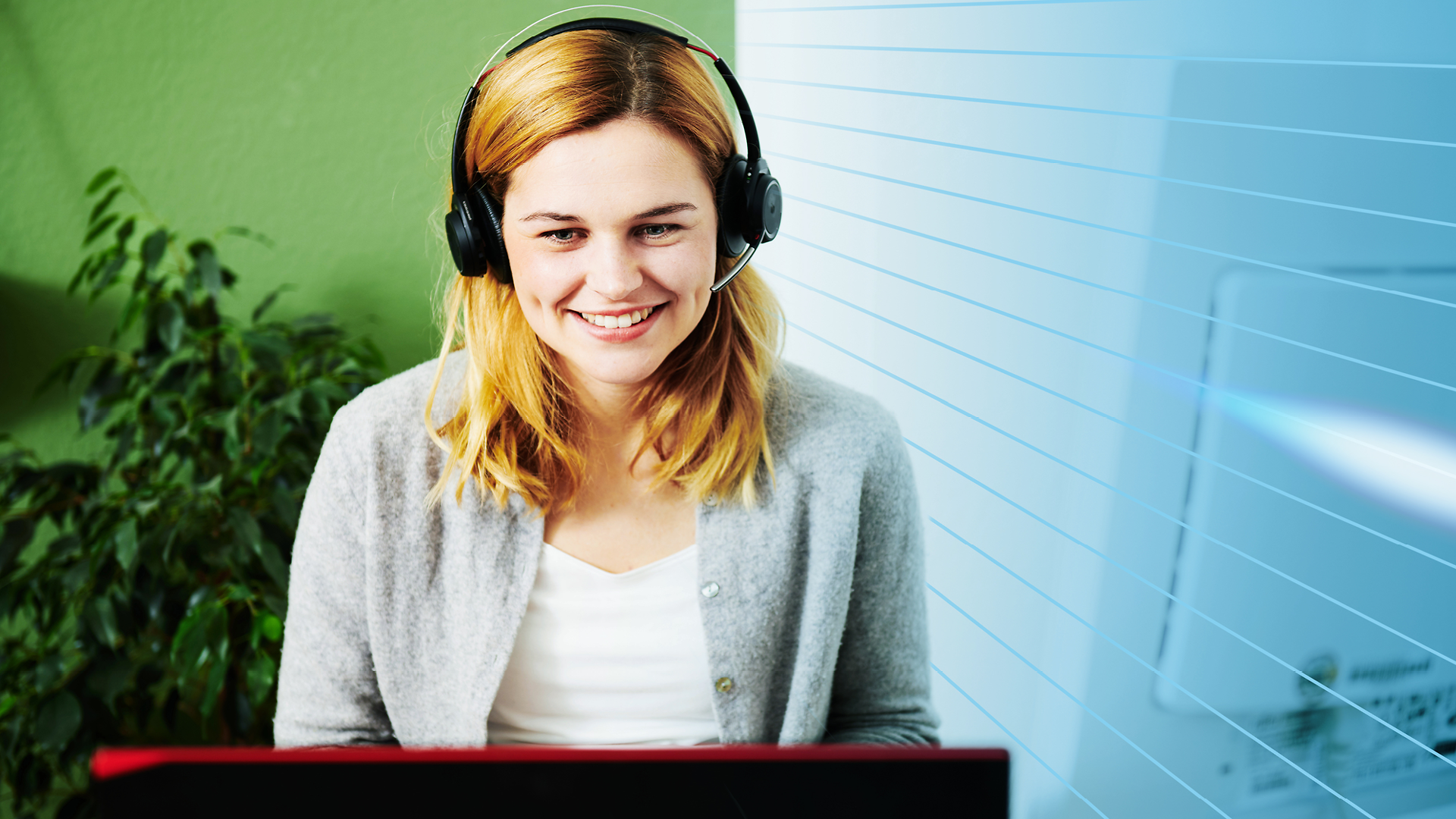 Frau lächelnd mit Headset vor einem PC sitzend