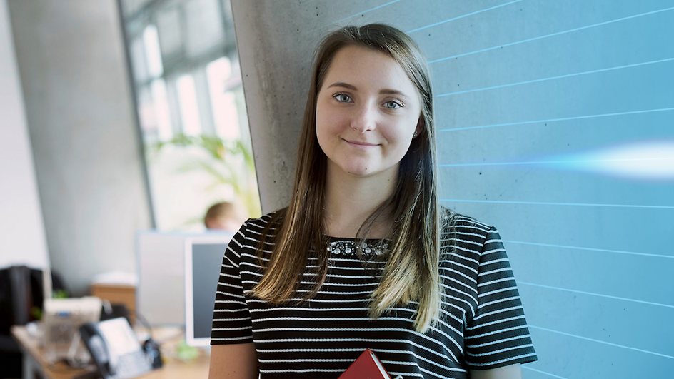 Schülerin im Büro stehend mit Buch in der Hand