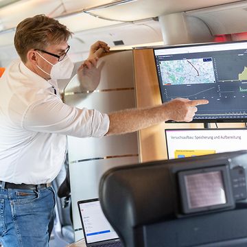 Man in train pointing at screen with data diagrams