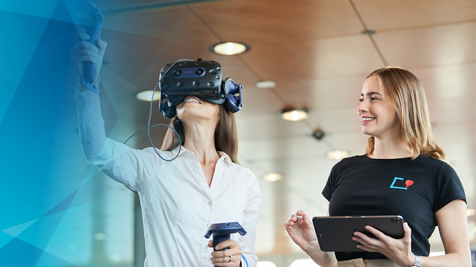 Frau mit VR-Brille auf, daneben zweite Frau mit Tablet in der Hand