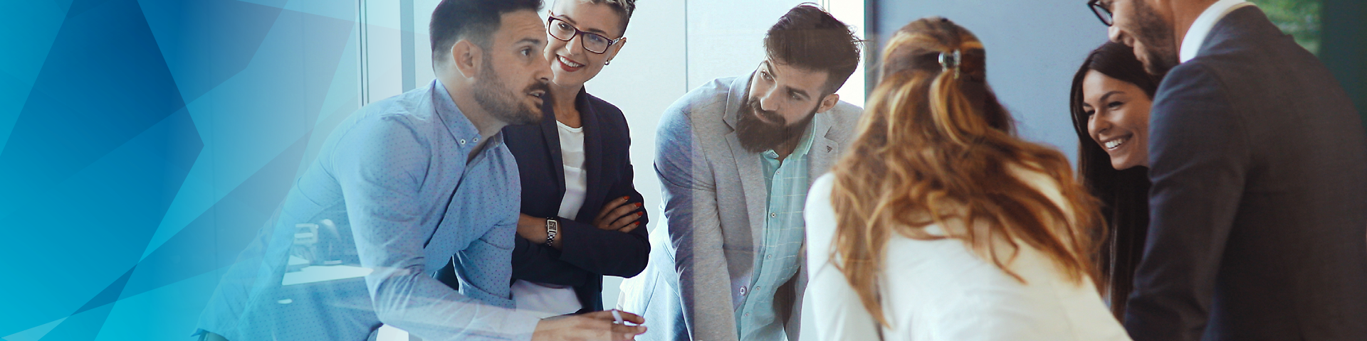 People standing and talking around a table with laptop in the middle