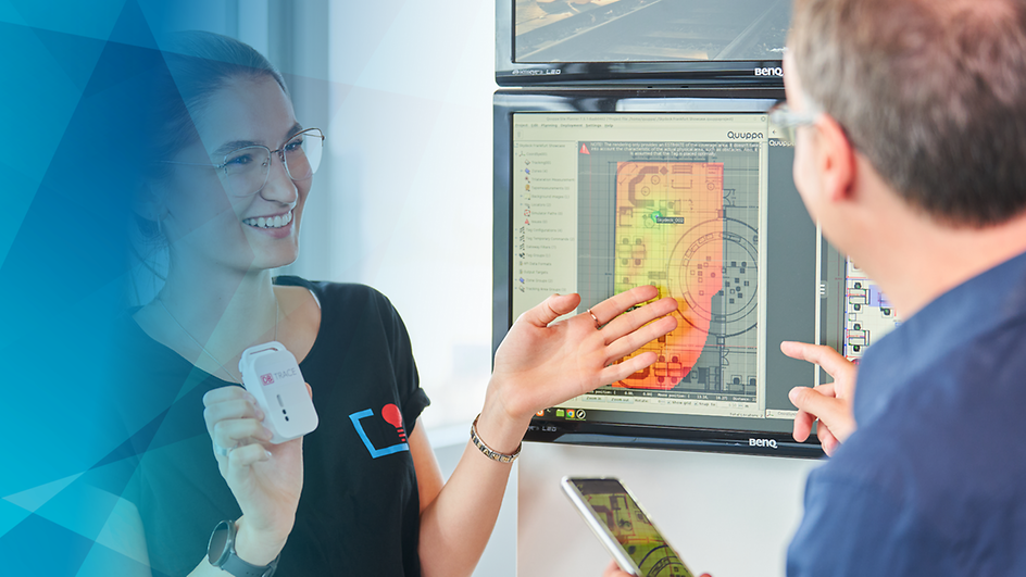 Skydeck-Mitarbeiterin mit TracE-Showcase in der Hand im Gespräch mit Mann.