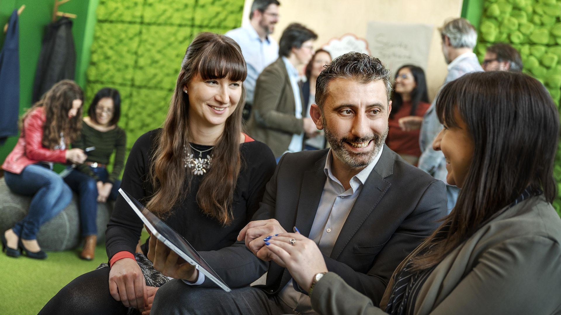 Mitarbeitende in einem Meeting mit Tablet in der Hand