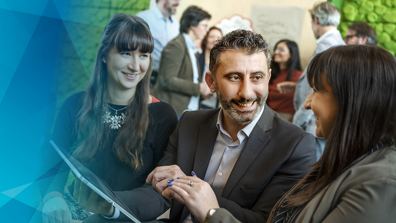Verschiedene Mitarbeitende in einem Meeting, in ein Tablet blickend